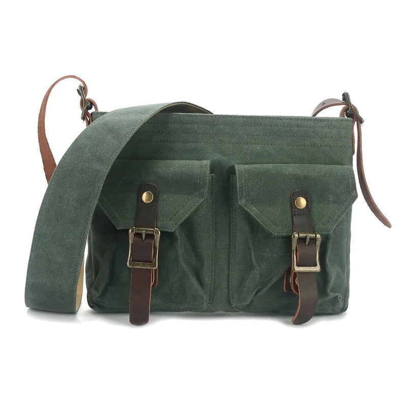 Borsa a tracolla verde in tela cerata con doppie tasche frontali e fibbie in pelle marrone. Design vintage, ideale per uomo e donna.