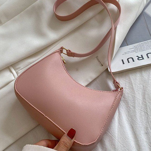 Borsa a tracolla rosa in pelle sintetica su tessuto bianco, design minimalista, ideale per moda femminile, accessorio elegante e versatile.