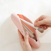 Custodia rosa per pennelli trucco con chiusura a bottone, contenente pennelli bianchi. Accessorio cosmetico essenziale per il make-up.