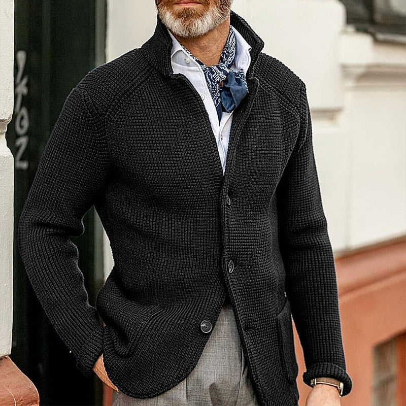 Giacca cardigan uomo in maglia nera, elegante e casual, abbinata a camicia bianca e cravatta blu. Moda autunnale maschile, stile sofisticato.