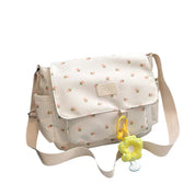 Borsa a tracolla bianca con stampa floreale, chiusura a patta, ciondolo a forma di fiore giallo, ideale per moda casual e accessori donna.