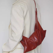 Borsa a tracolla in pelle rossa su cappotto bianco, design moderno ed elegante. Accessorio moda donna, stile contemporaneo, alta qualità.
