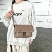 Donna con borsa a tracolla beige, indossa felpa grigia con scritta. Design moderno, casual, perfetto per moda urbana e quotidiana.