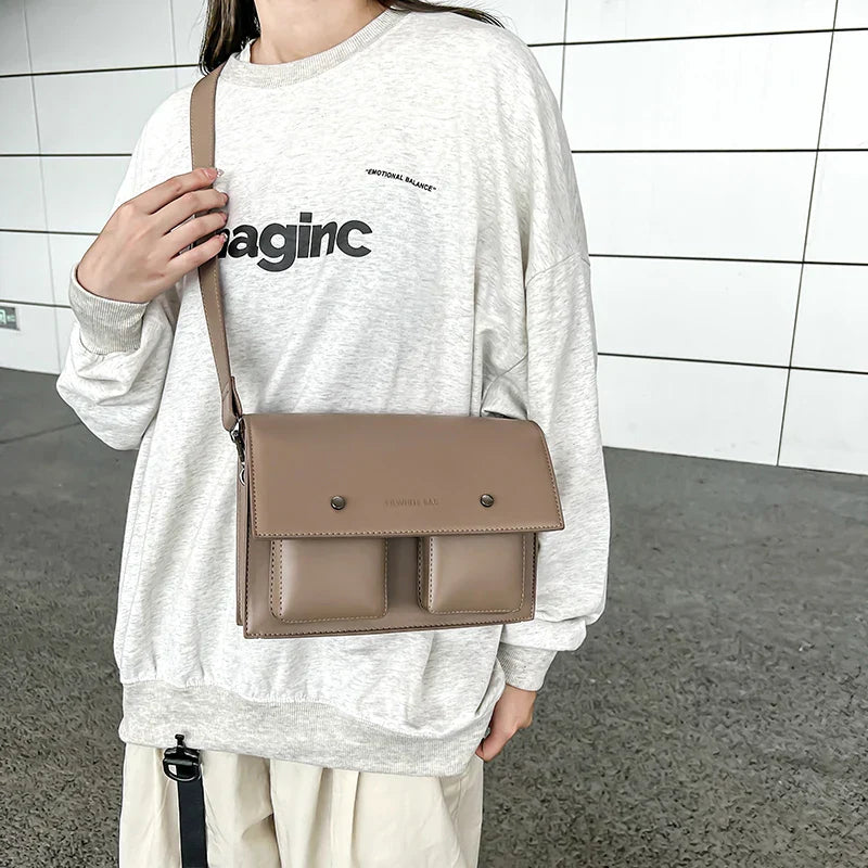 Donna con borsa a tracolla beige, indossa felpa grigia con scritta. Design moderno, casual, perfetto per moda urbana e quotidiana.