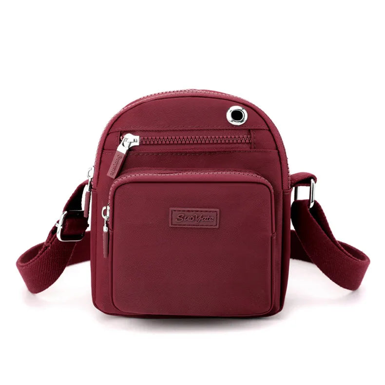 Borsa a tracolla rossa in tessuto impermeabile, design compatto con tasche multiple e cerniere, ideale per viaggi e uso quotidiano.