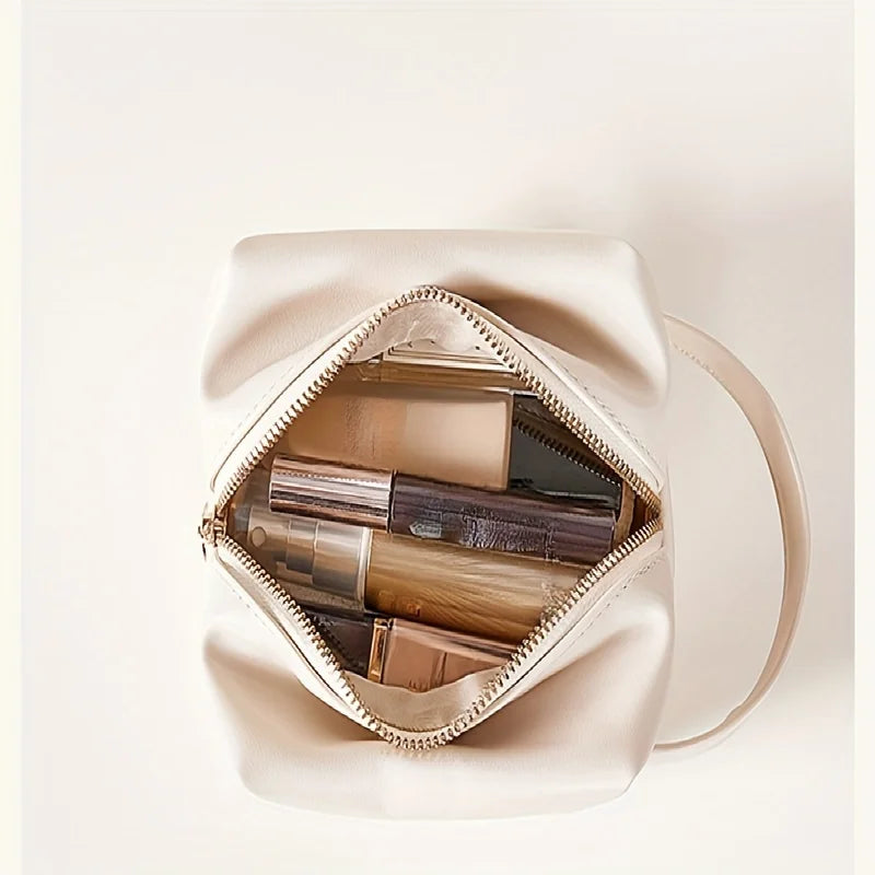 Borsa cosmetica beige aperta con vari prodotti di bellezza all'interno, tra cui flaconi e tubetti. Accessorio moda donna, organizzazione trucco.