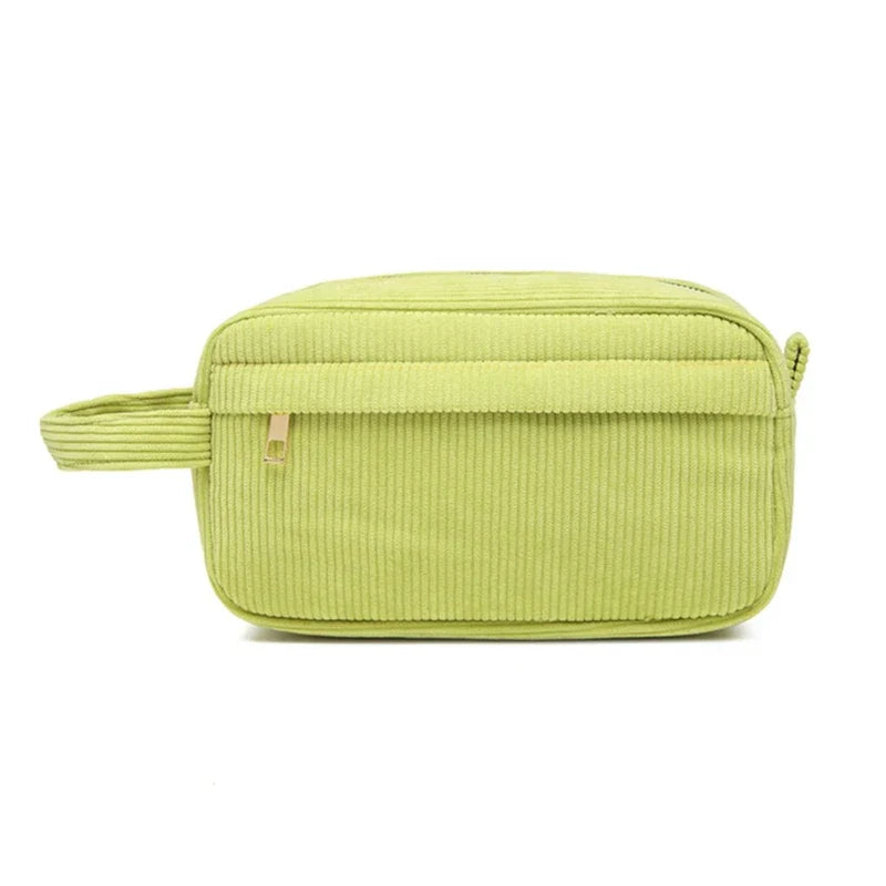 Borsa da toilette verde in velluto a coste con cerniera, manico laterale e design rettangolare. Accessorio da viaggio elegante e pratico.