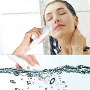 Donna utilizza spazzola elettrica per pulizia viso sotto la doccia, impermeabile, ricaricabile, cura della pelle, esfoliazione, bellezza quotidiana.