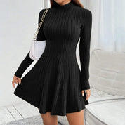 Abito nero a coste, maniche lunghe, collo alto, con borsa bianca a catena. Elegante vestito invernale da donna, moda casual chic.