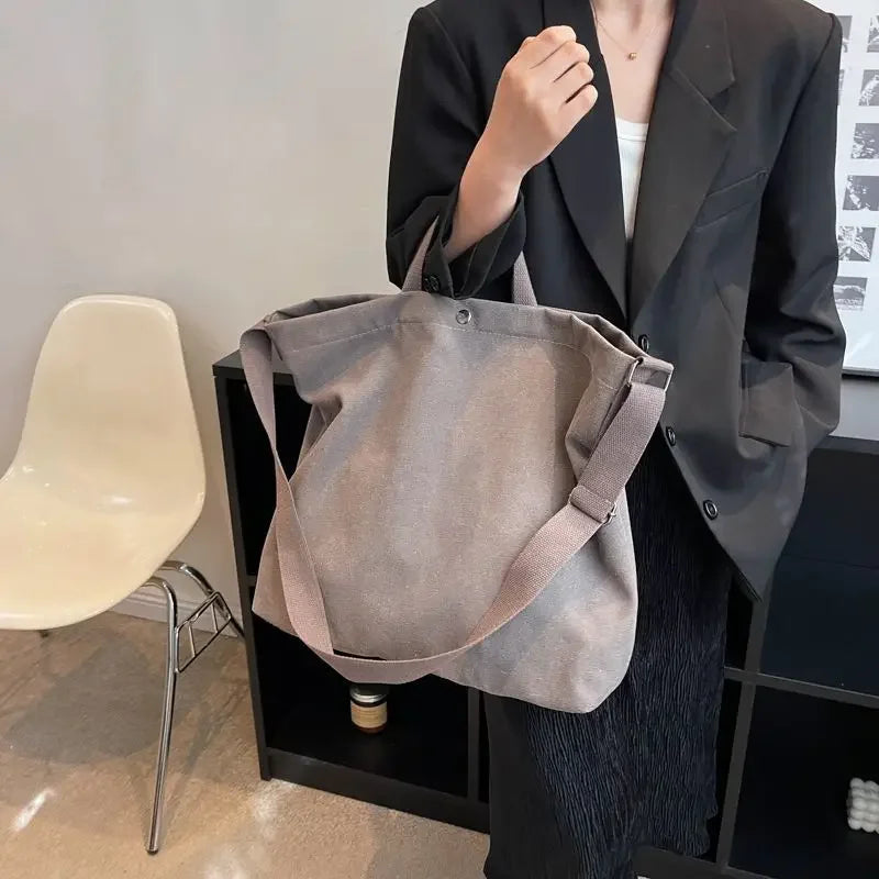 Donna con borsa a tracolla grigia in tessuto, indossa giacca nera. Accessorio moda casual, ideale per shopping e uso quotidiano.