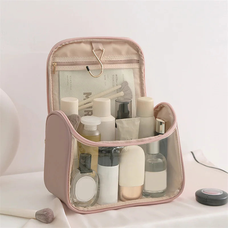 Beauty case trasparente rosa con prodotti cosmetici, ideale per viaggi. Include flaconi, creme e accessori trucco. Organizzazione pratica ed elegante.