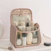 Beauty case trasparente rosa con prodotti cosmetici, ideale per viaggi. Include flaconi, creme e accessori trucco. Organizzazione pratica ed elegante.