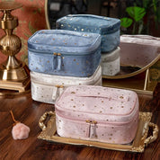 Set di beauty case in velluto con stelle dorate, colori pastello, su vassoio dorato. Elegante accessorio da viaggio, ideale per cosmetici e gioielli.