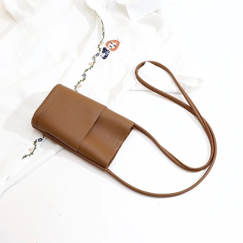 Borsa a tracolla in pelle marrone su sfondo bianco, design minimalista, ideale per moda donna, accessorio elegante e versatile.