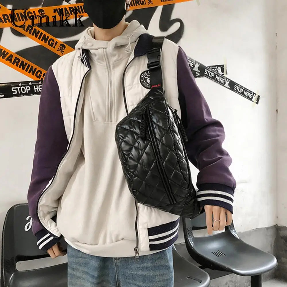 Giacca varsity bianca e viola, felpa con cappuccio bianca, borsa a tracolla nera trapuntata, moda streetwear uomo, stile casual urbano.