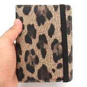 Portafoglio compatto con stampa leopardata, chiusura elastica nera, tenuto in mano. Accessorio moda elegante e pratico per donna.