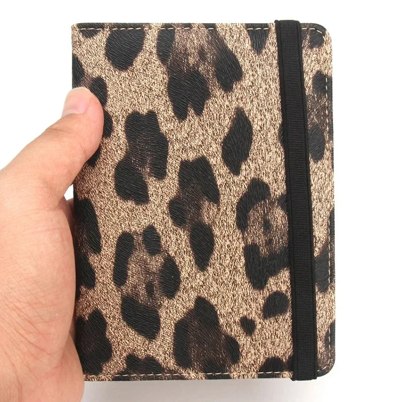 Portafoglio compatto con stampa leopardata, chiusura elastica nera, tenuto in mano. Accessorio moda elegante e pratico per donna.