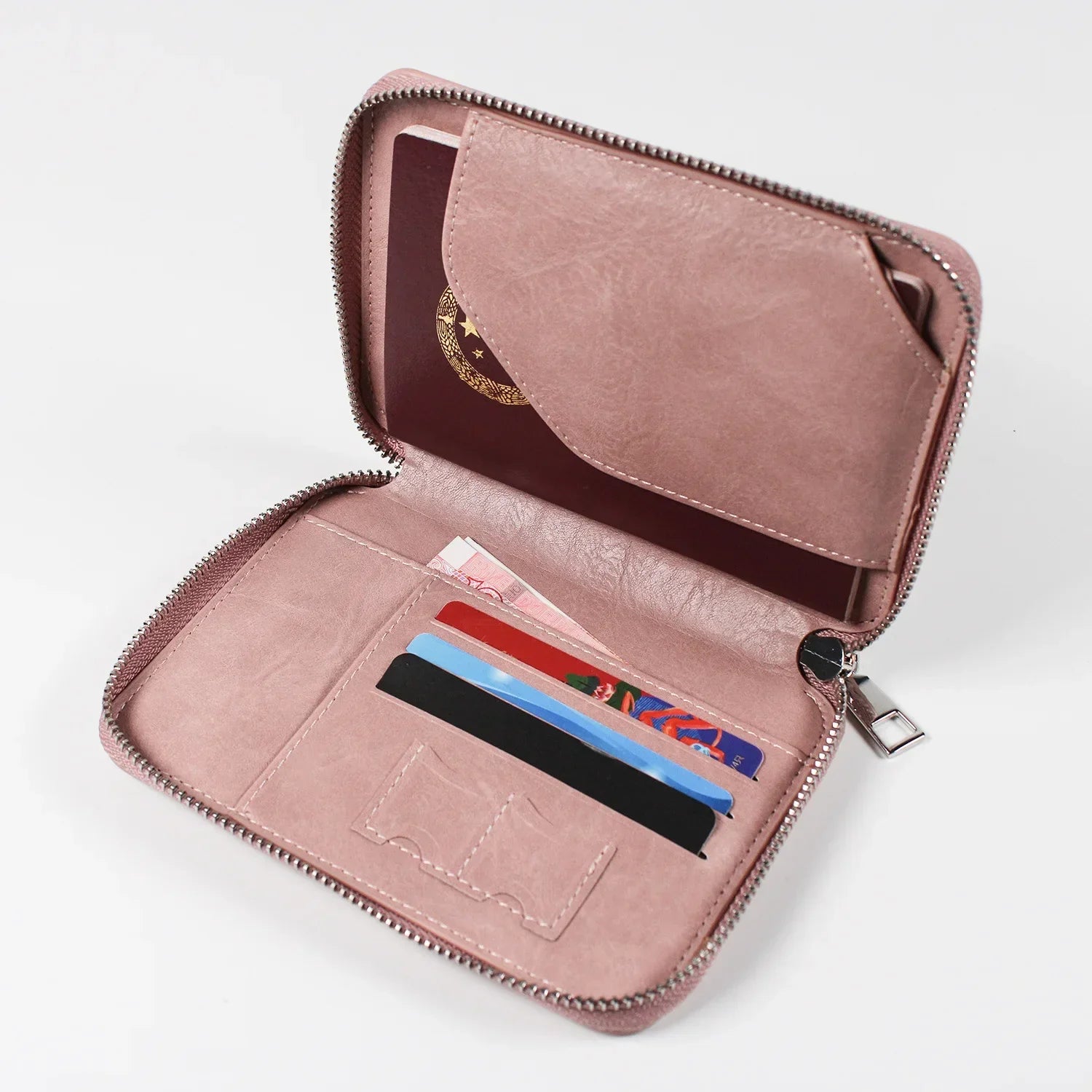 Portafoglio in pelle rosa con cerniera, scomparti per carte di credito e tasca per passaporto. Accessorio elegante e funzionale per viaggiatori.