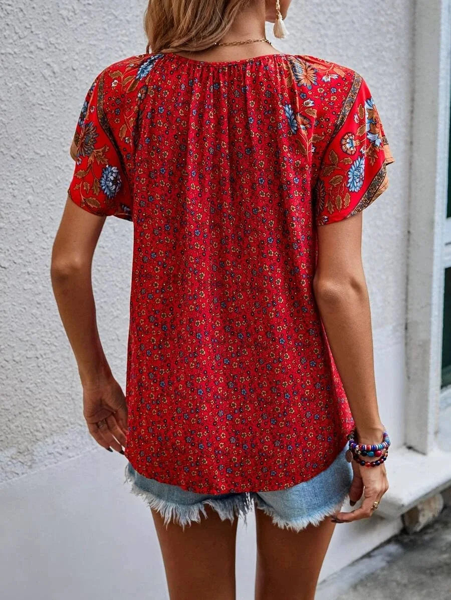 Donna con blusa rossa a fiori, maniche corte, abbinata a shorts di jeans. Moda estiva casual, abbigliamento femminile trendy.