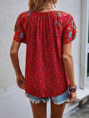 Donna con blusa rossa a fiori, maniche corte, abbinata a shorts di jeans. Moda estiva casual, abbigliamento femminile trendy.