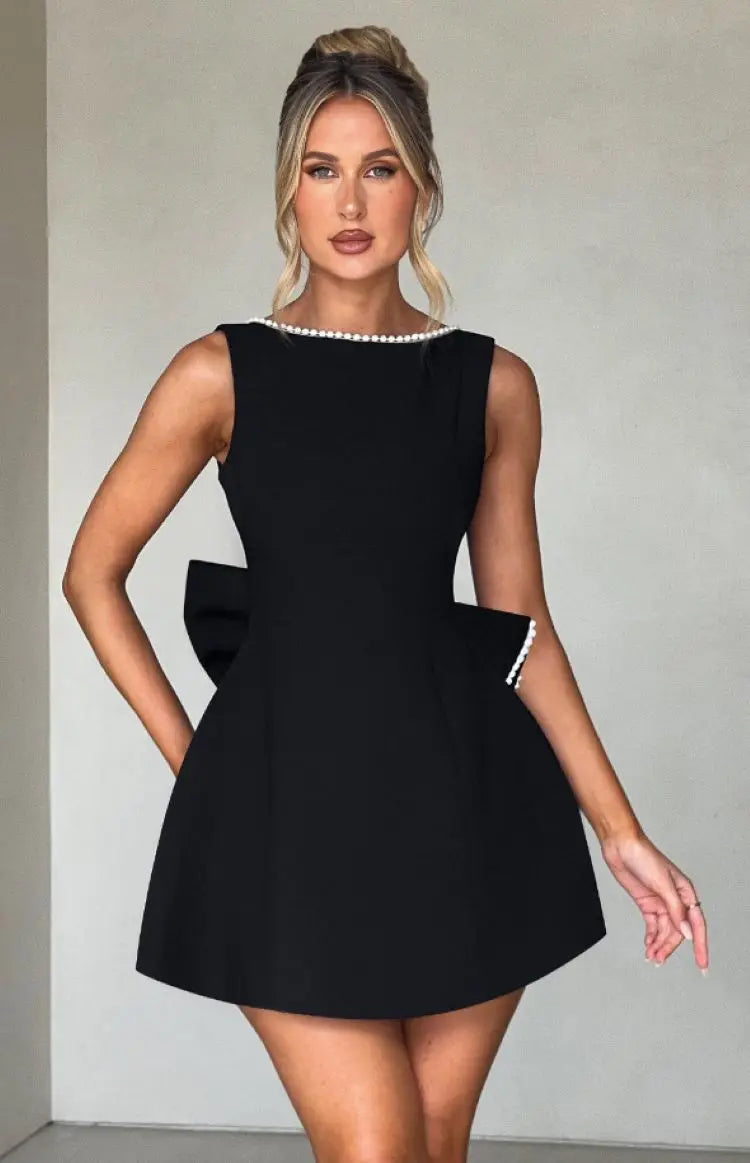Abito nero elegante da donna con perle, senza maniche, design a fiocco, perfetto per eventi formali e serate glamour. Moda femminile chic.