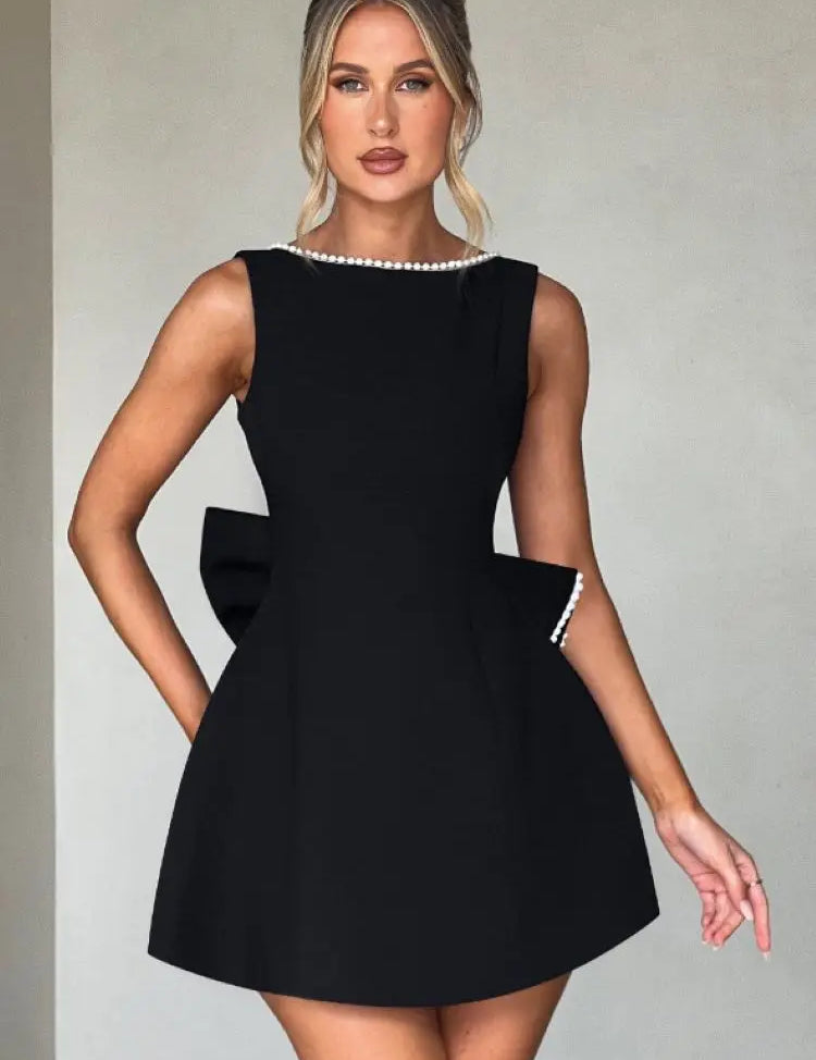 Abito nero elegante da donna con perle, senza maniche, design a fiocco, perfetto per eventi formali e serate glamour. Moda femminile chic.