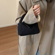 Cappotto beige elegante, borsa a tracolla nera con cerniera e catena argentata, moda donna autunno, stile minimalista, accessori di tendenza.
