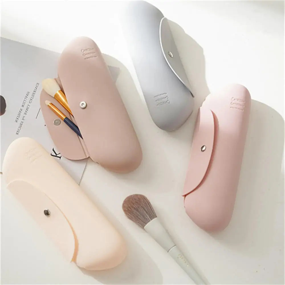 Quattro astucci porta pennelli in silicone color pastello con chiusura a bottone, ideali per organizzare pennelli trucco. Design elegante e funzionale.