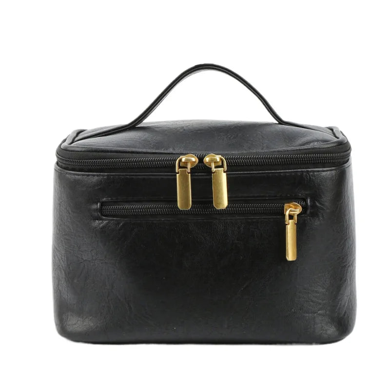 Borsa cosmetica nera in pelle sintetica con doppia cerniera dorata, manico superiore. Elegante e pratica per viaggi e organizzazione trucco.