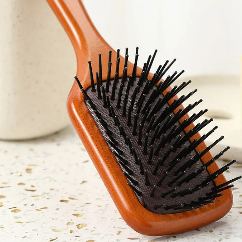 Spazzola per capelli in legno con setole nere, design ergonomico, ideale per districare e lisciare, accessorio essenziale per la cura dei capelli.