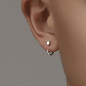 Orecchino a cerchio minimalista in argento su lobo, design moderno, gioielli eleganti, accessori moda, stile contemporaneo, dettaglio orecchio.