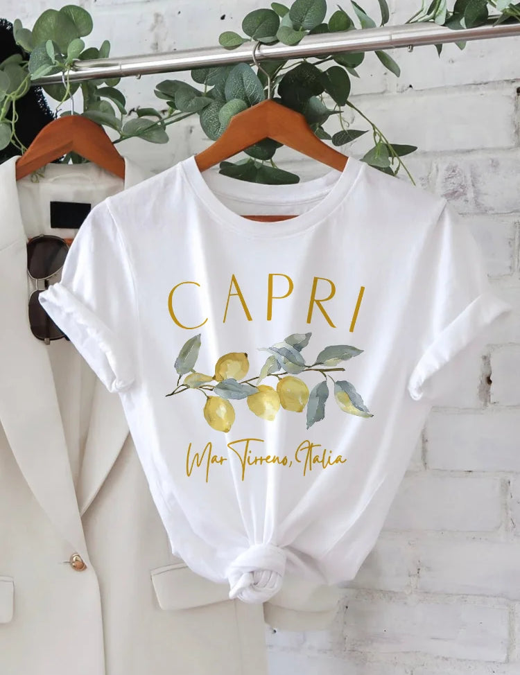 Maglietta bianca con stampa "Capri" e limoni, appesa su gruccia. Design estivo, moda casual, abbigliamento donna, ispirazione italiana.