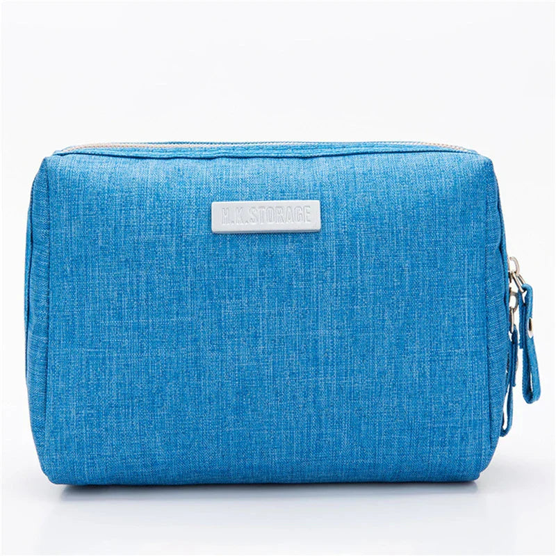 Astuccio da viaggio blu in tessuto, con cerniera e etichetta "M. STORAGE". Ideale per organizzare accessori e cosmetici. Design compatto e pratico.