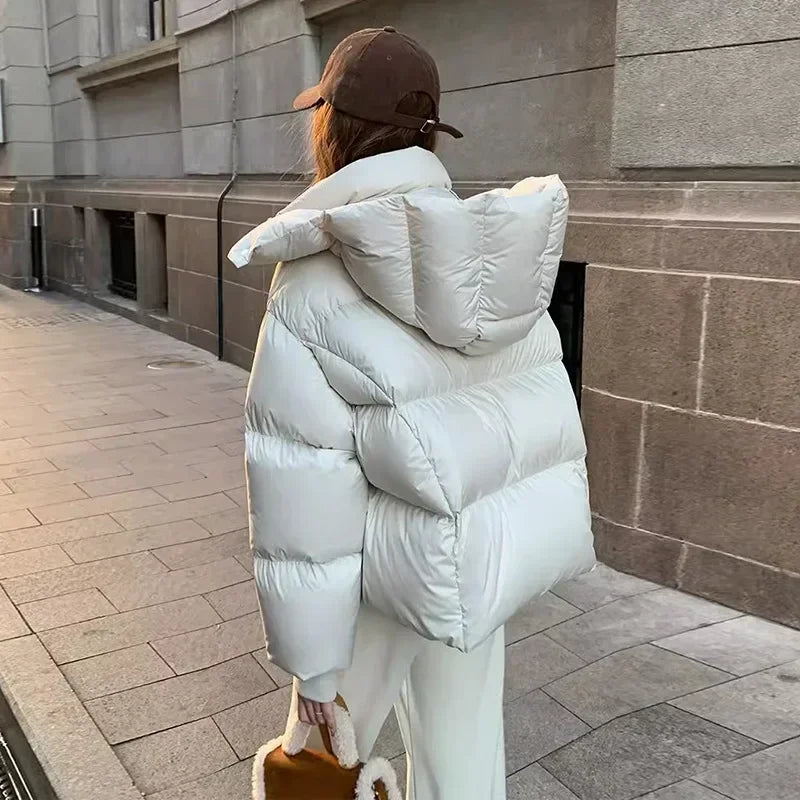 Giacca invernale donna bianca, imbottita e con cappuccio, indossata all'aperto. Moda casual, cappotto caldo, stile urbano.