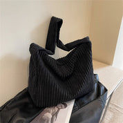 Borsa a spalla in velluto a coste nero su sfondo chiaro, design moderno e capiente. Accessorio moda donna, elegante e versatile.