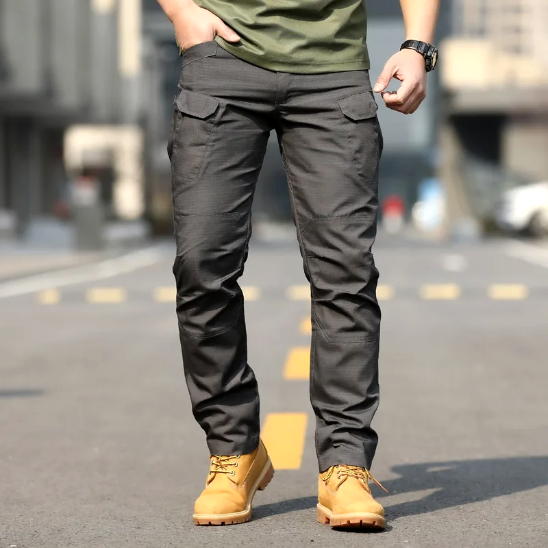Pantaloni cargo uomo grigi, tasche multiple, indossati con stivali gialli su strada urbana. Abbigliamento casual maschile, moda outdoor.