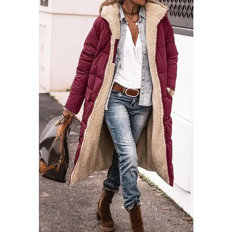 Donna con cappotto lungo imbottito bordeaux, camicia bianca, jeans e stivali marroni. Moda invernale casual, look urbano elegante.