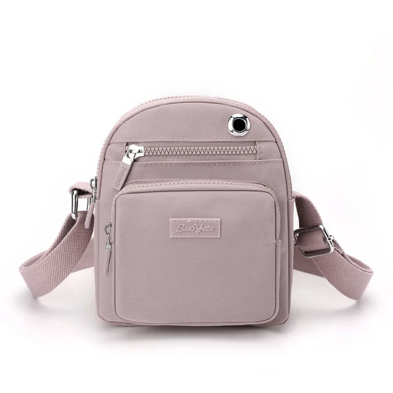 Zaino compatto rosa chiaro in pelle sintetica, con tasche multiple e tracolla regolabile. Design elegante e pratico per uso quotidiano.