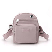 Zaino compatto rosa chiaro in pelle sintetica, con tasche multiple e tracolla regolabile. Design elegante e pratico per uso quotidiano.