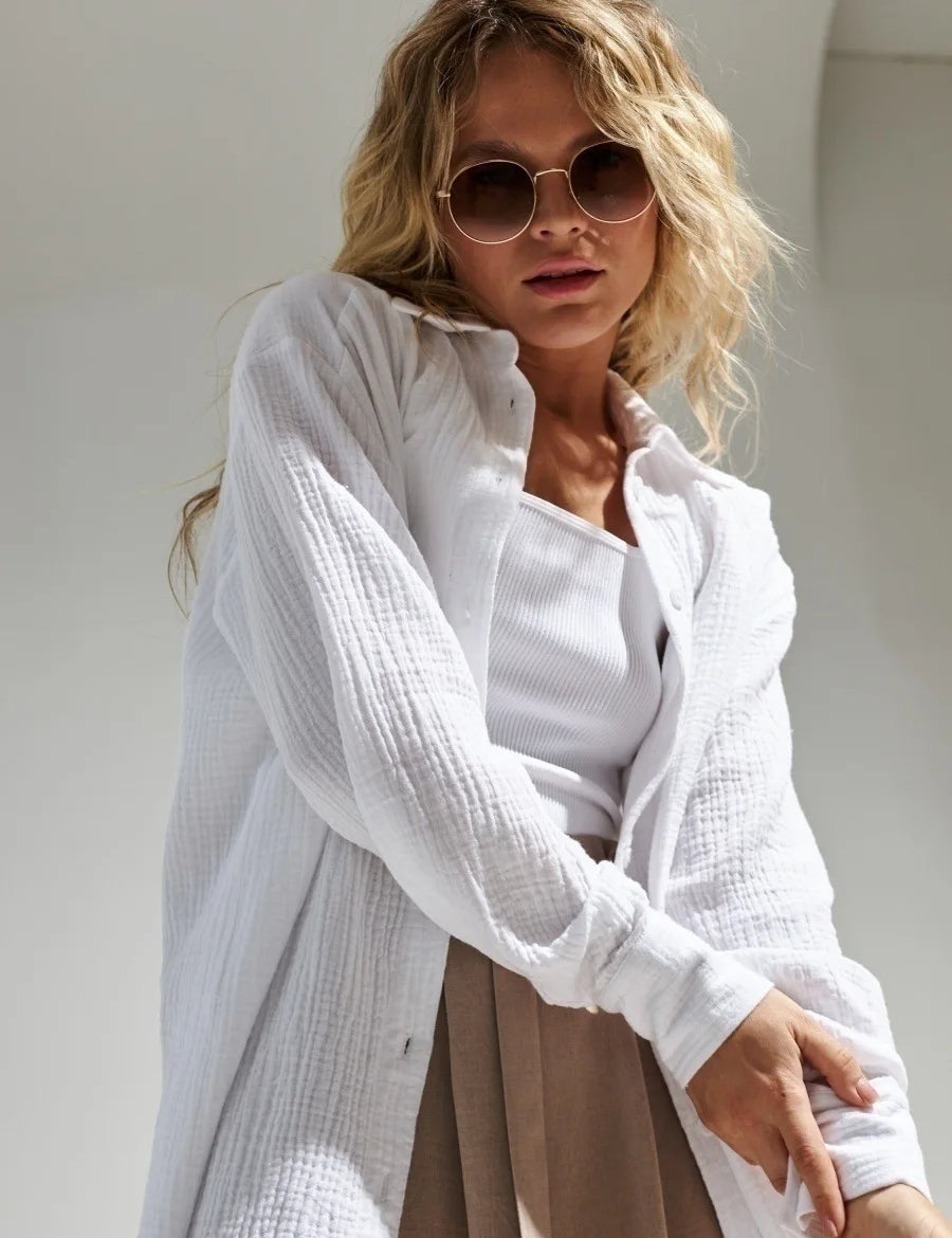 Donna con camicia bianca in cotone, top bianco e occhiali da sole rotondi. Moda estiva casual, look elegante e moderno. Sfondo neutro.