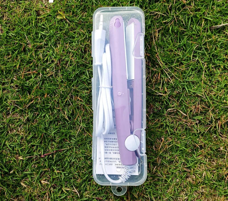 Piastra per capelli portatile viola in custodia trasparente su erba, con cavo di alimentazione e manuale. Ideale per viaggi e styling veloce.
