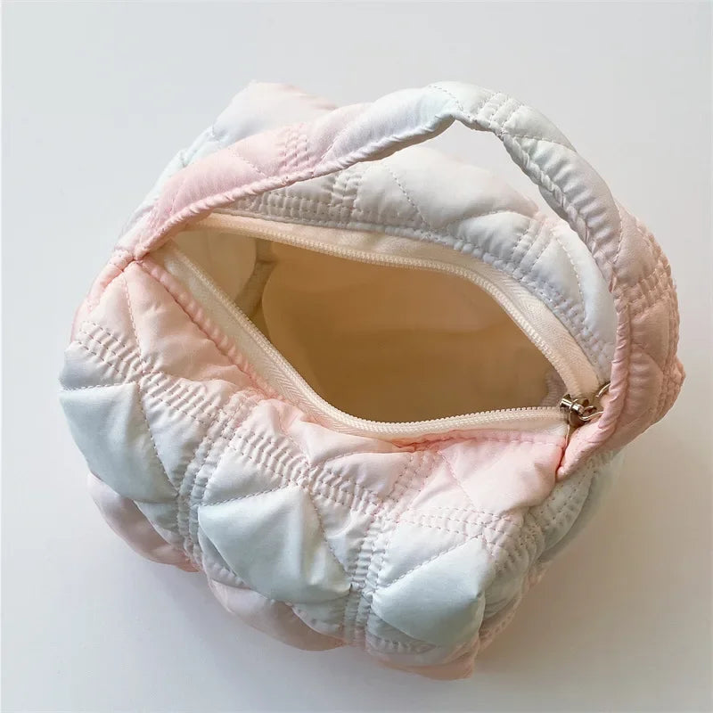 Borsa trapuntata in tessuto pastello, design a nuvola, con cerniera aperta. Accessorio moda donna, elegante e moderno.
