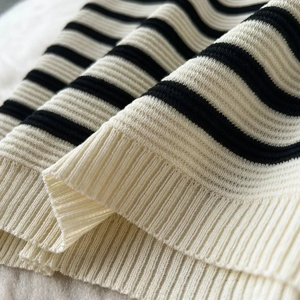Maglione a righe bianche e nere in lana, tessuto a coste, moda autunno inverno, abbigliamento casual elegante, dettaglio texture morbida.