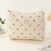 Borsa trapuntata beige con motivo floreale rosso, etichetta "today, mood feel the warm", su sfondo chiaro. Accessorio moda elegante e pratico.