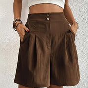 Pantaloncini marroni a vita alta, stile casual, con tasche laterali e pieghe, indossati da una donna. Ideali per moda estiva e look rilassato.