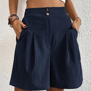 Shorts donna blu scuro a vita alta con tasche, bottoni decorativi, tessuto leggero e pieghe eleganti. Ideali per moda estiva casual.