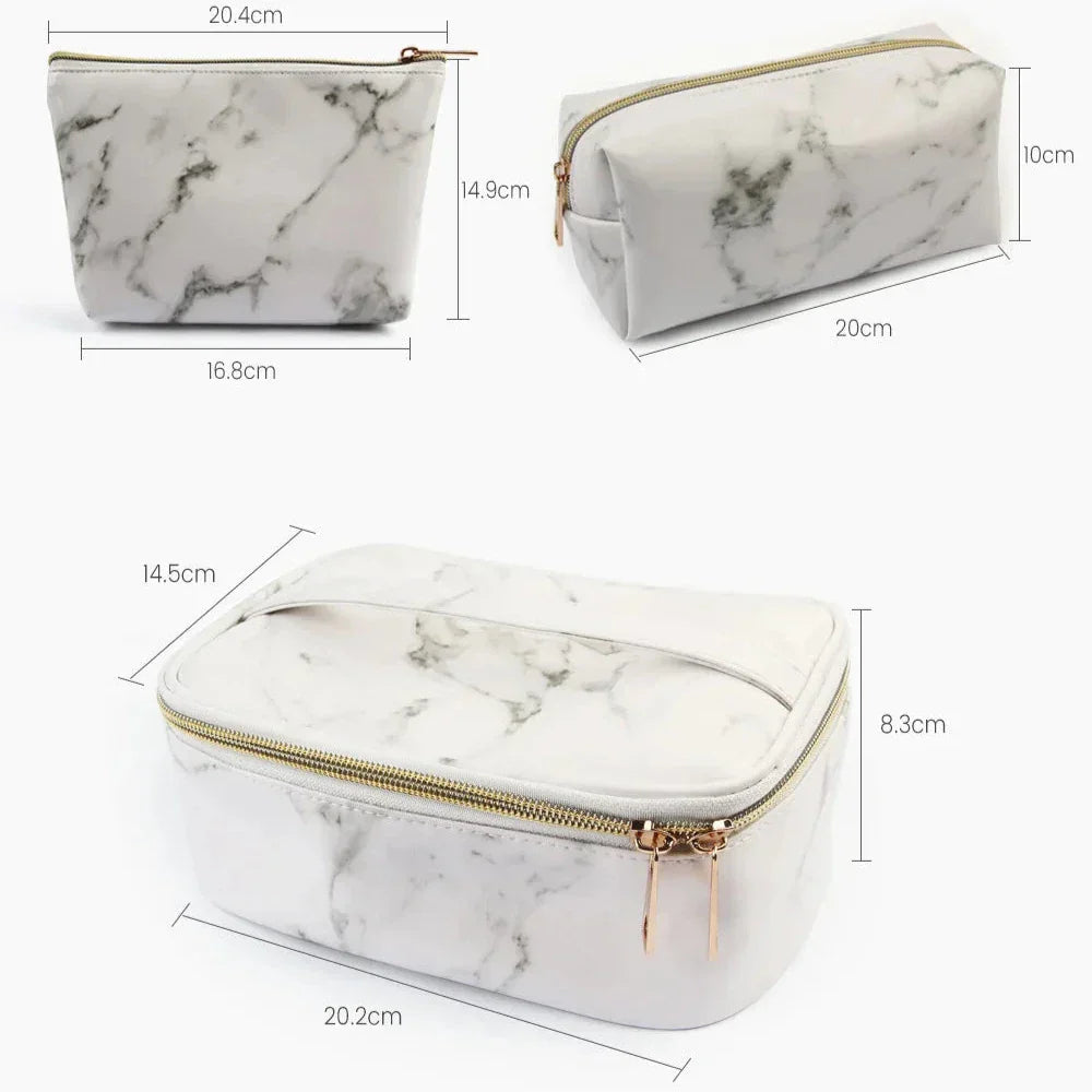 Set di tre beauty case in ecopelle effetto marmo bianco, con cerniera dorata. Dimensioni: 20x10x14 cm, 20x8.3x14.5 cm, 16.8x14.9x20.4 cm.