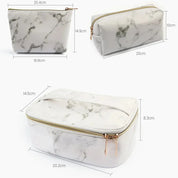 Set di tre beauty case in ecopelle effetto marmo bianco, con cerniera dorata. Dimensioni: 20x10x14 cm, 20x8.3x14.5 cm, 16.8x14.9x20.4 cm.