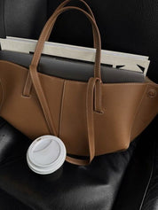 Borsa in pelle marrone su sedile auto con caffè da asporto e laptop. Accessori moda eleganti, borsa capiente, stile urbano.