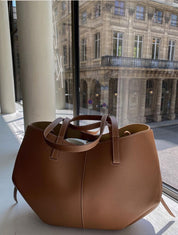 Borsa a mano in pelle marrone su sfondo urbano, design elegante e moderno, perfetta per moda donna, accessori di lusso, shopping e ufficio.